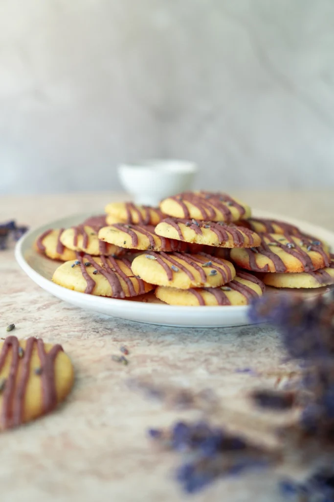 Lavender cookies stacked on a serving plate with purple icing drizzle.