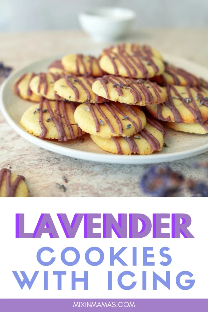 Lavender cookies with icing stacked on a plate with purple icing drizzle and dried lavender buds