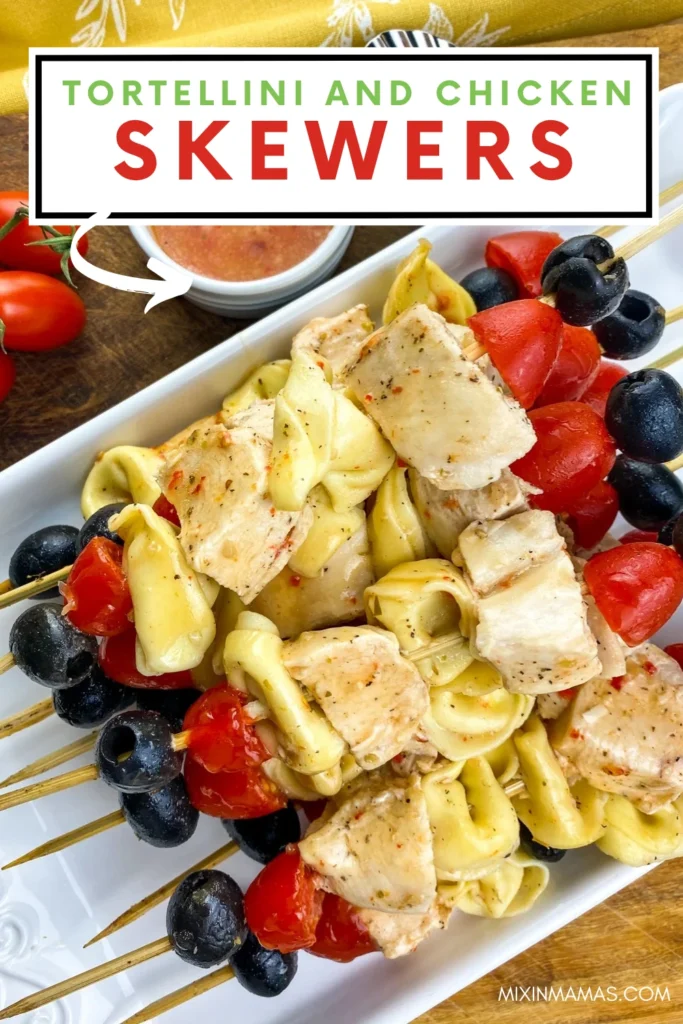 Close-up Pinterest image of tortellini chicken skewers served with grape tomatoes, black olives, and Italian dressing.