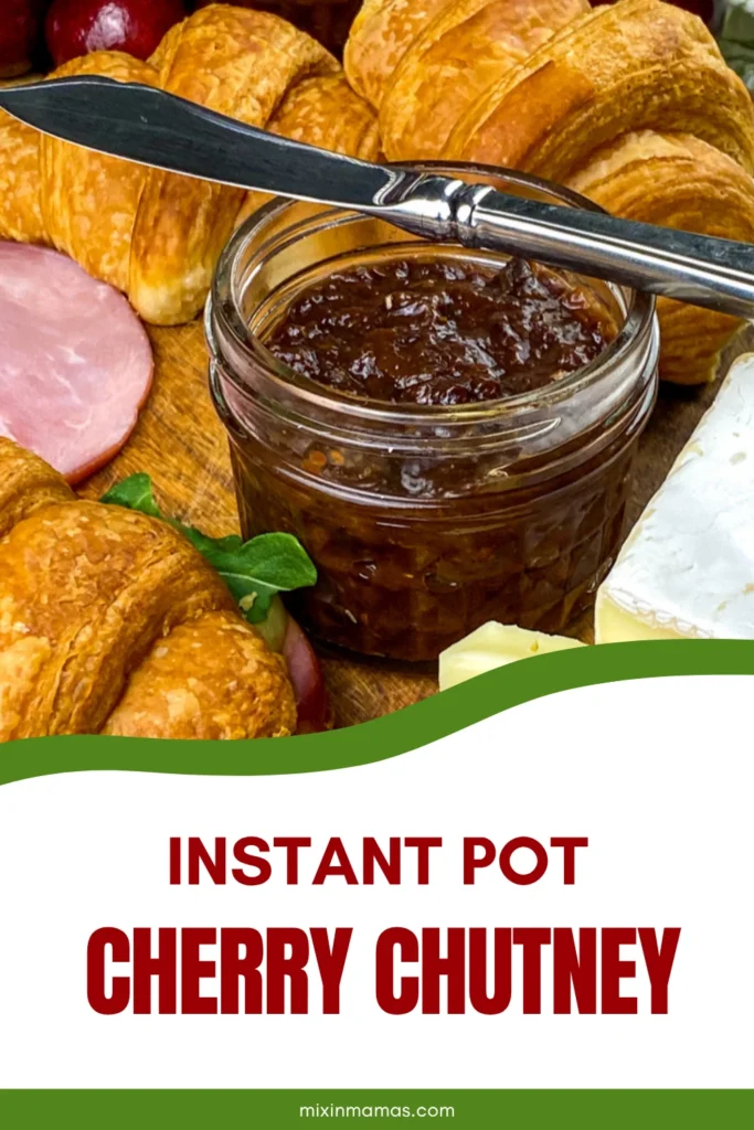 Jar of homemade Instant Pot cherry chutney served with Brie cheese, croissants, and ham on a charcuterie board.