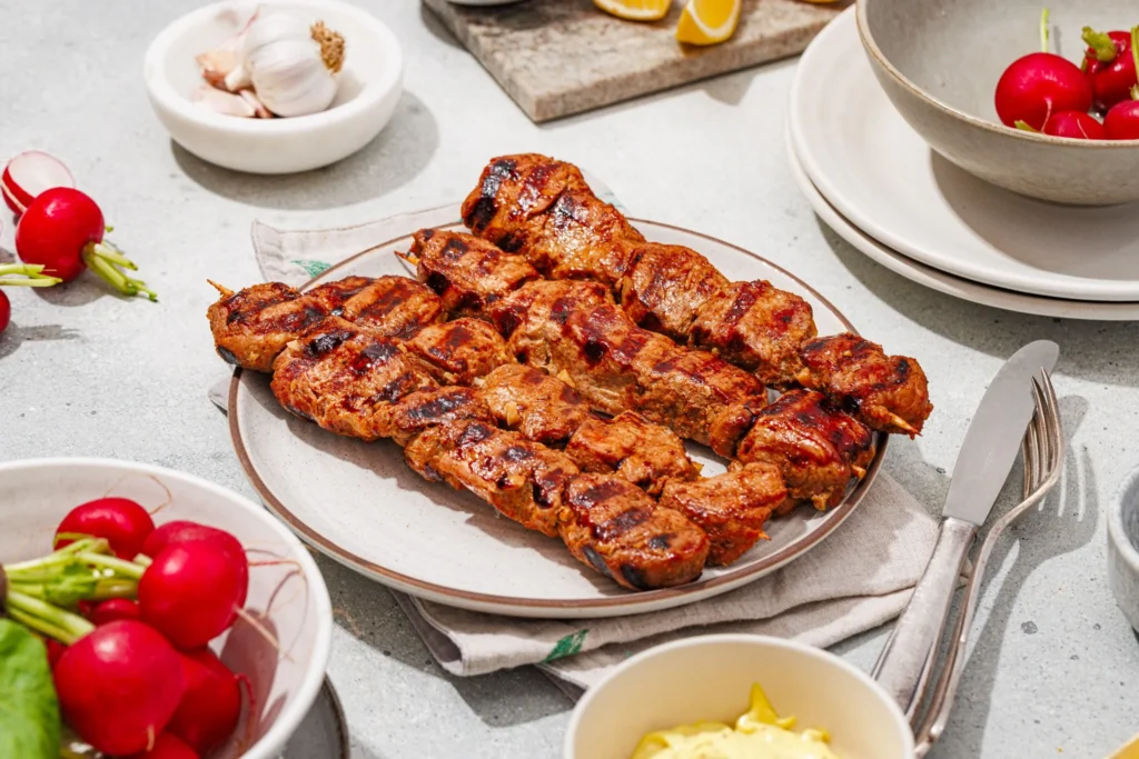Grilled pork skewers with charred edges served with homemade aioli.