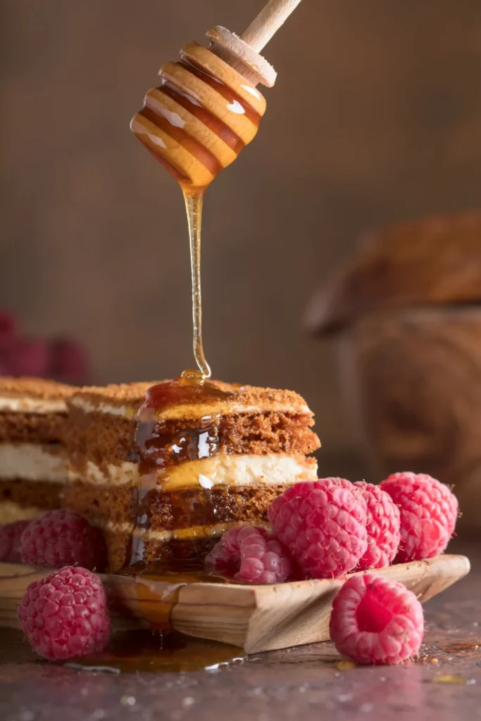 Honey drizzled over layered spice cake with fresh raspberries