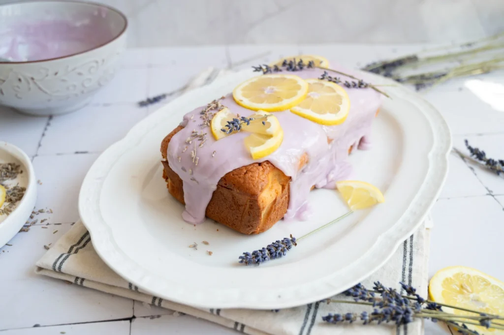 Lemon lavender pound cake topped with purple glaze, fresh lemon slices, and lavender.