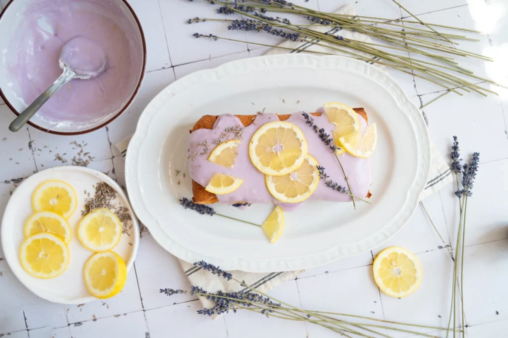 Lemon lavender pound cake topped with pale purple glaze, fresh lemon slices, and lavender sprigs.