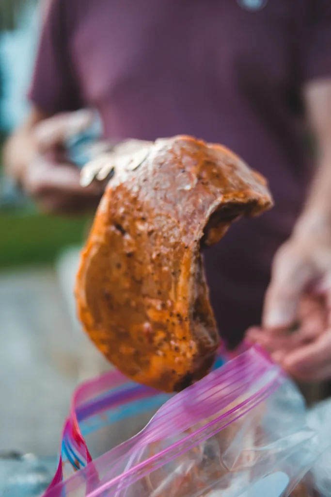 Marinated steak being removed from a resealable bag before grilling