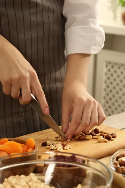 Chopping mixed nuts on a cutting board to use in recipes